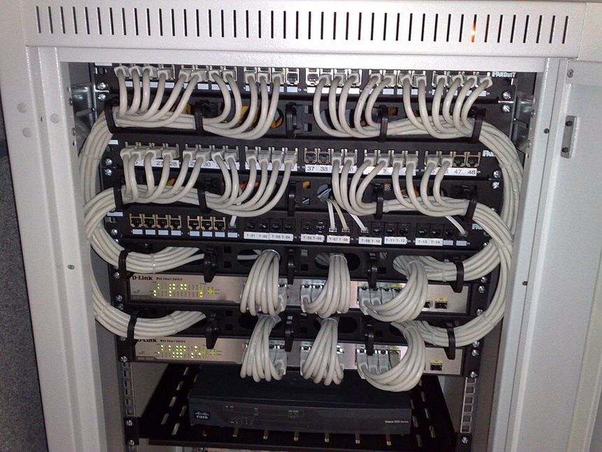 Rackmount Ethernet switches with dozens of patch cables running into a panel.