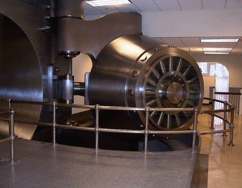 The open steel vault door of the Cleveland Federal Reserve Bank, a polished cylinder several feet thick, displayed behind a railing in a public lobby.